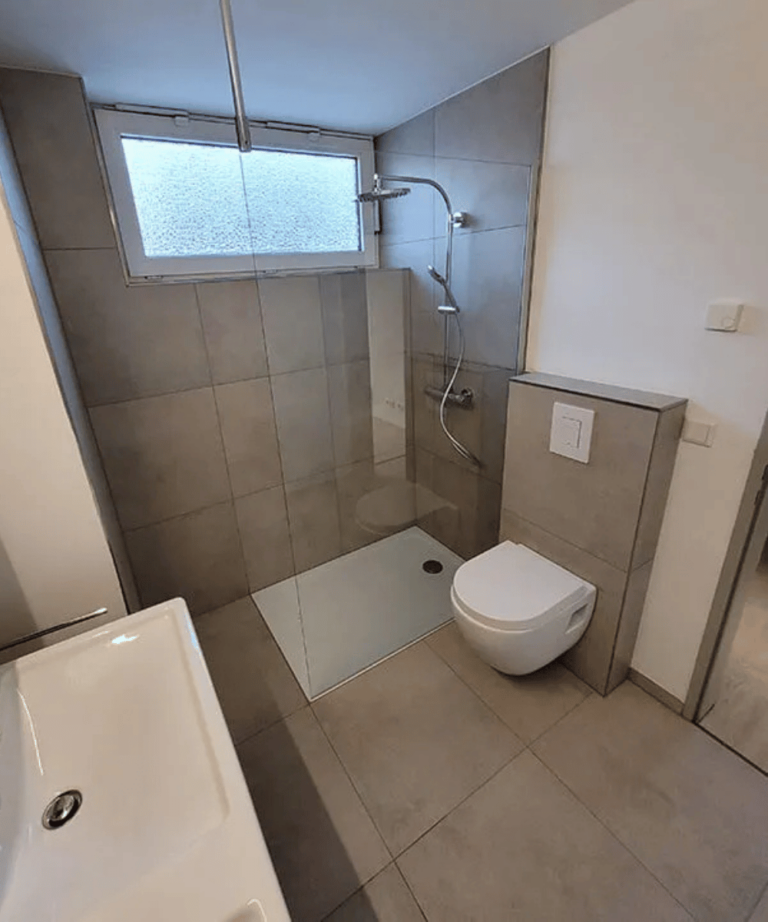 Modern saniertes Badezimmer mit grauen Fliesen und eleganter Ausstattung